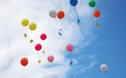 Luftballons mit Händen vor blauem Himmel